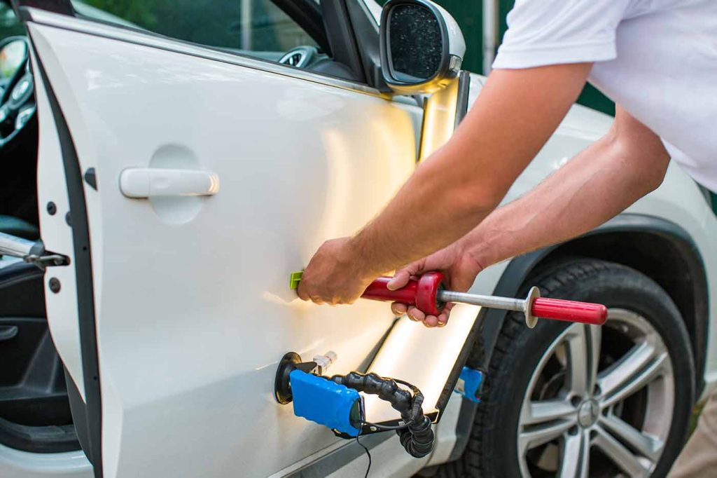 Technician assessing collision repairs in auto body shop