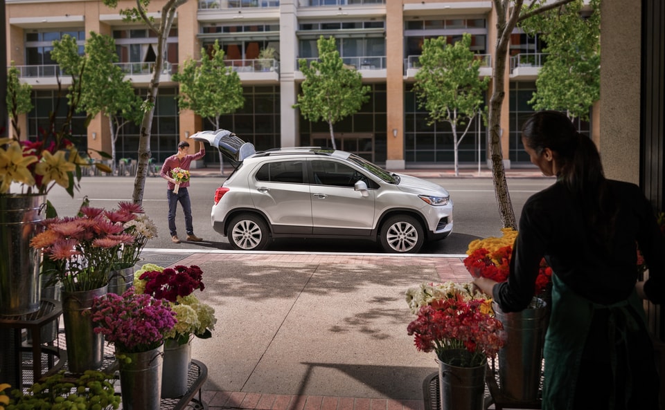 Man at flower shop putting bouquet in trunk of Chevy SUV